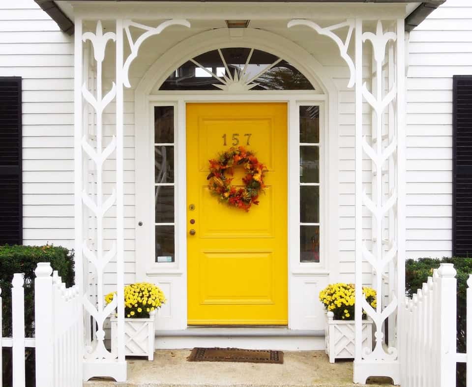 Yellow front door of white house, with a wreath